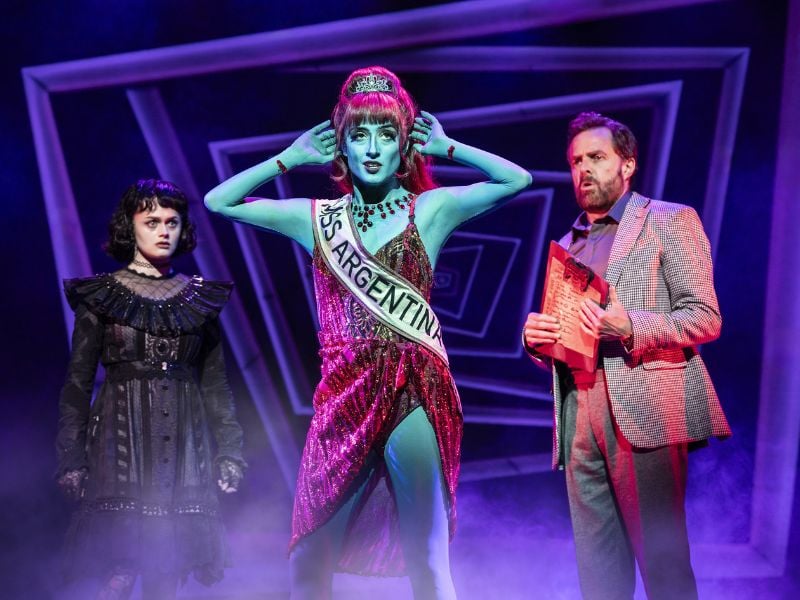 Hannah Nordberg as Lydia Deetz, Vanessa Aurora Sierra as Miss Argentina and Alasdair Harvey as Charles Deetz in Beetlejuice, West End © Johan Persson