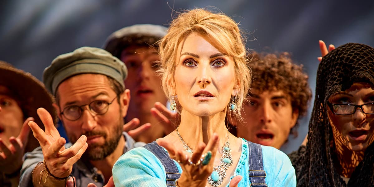 Donna and the cast of MAMMA MIA! are stood next to each other, looking up to the camera with hands extended