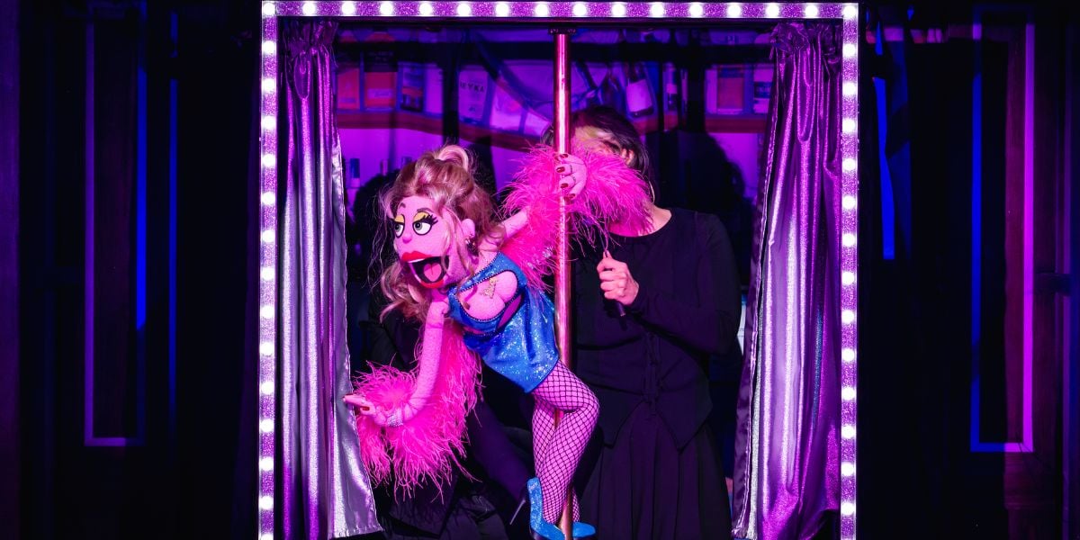 Production shot of Lucy The Slut in Avenue Q . The puppet is pink with a blonde wig and a tight fitting blue dress and a purple feather boa.Photo by Matt Crockett