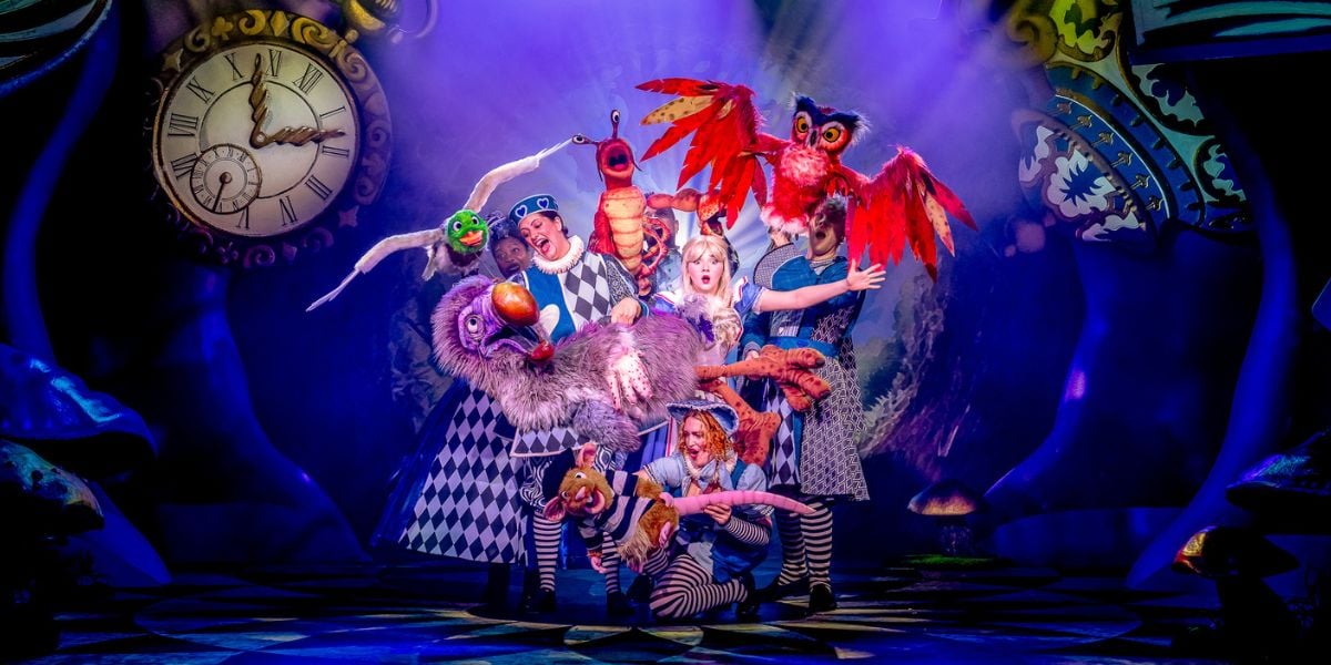 The ensemble of Alice in Wonderland at Riverside Studios. The cast surround Alice (Charlotte Bradley) menacingly.