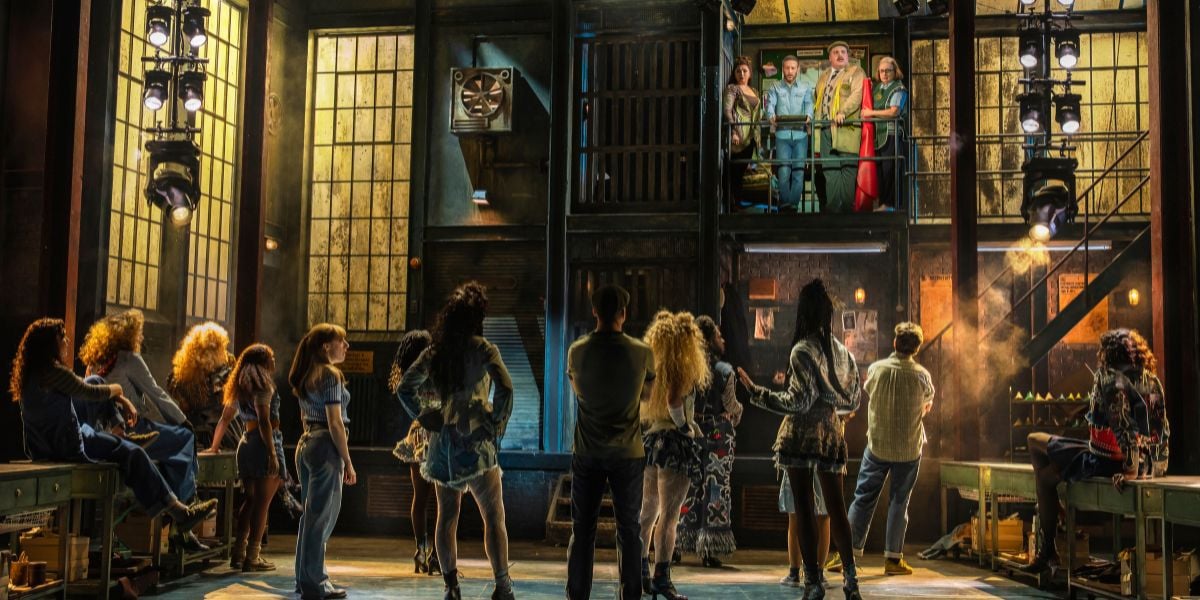 The company of Kinky Boots, their backs towards the audience they look up towards Matt Cardle as Charlie Price surrounded by his other colleagues.