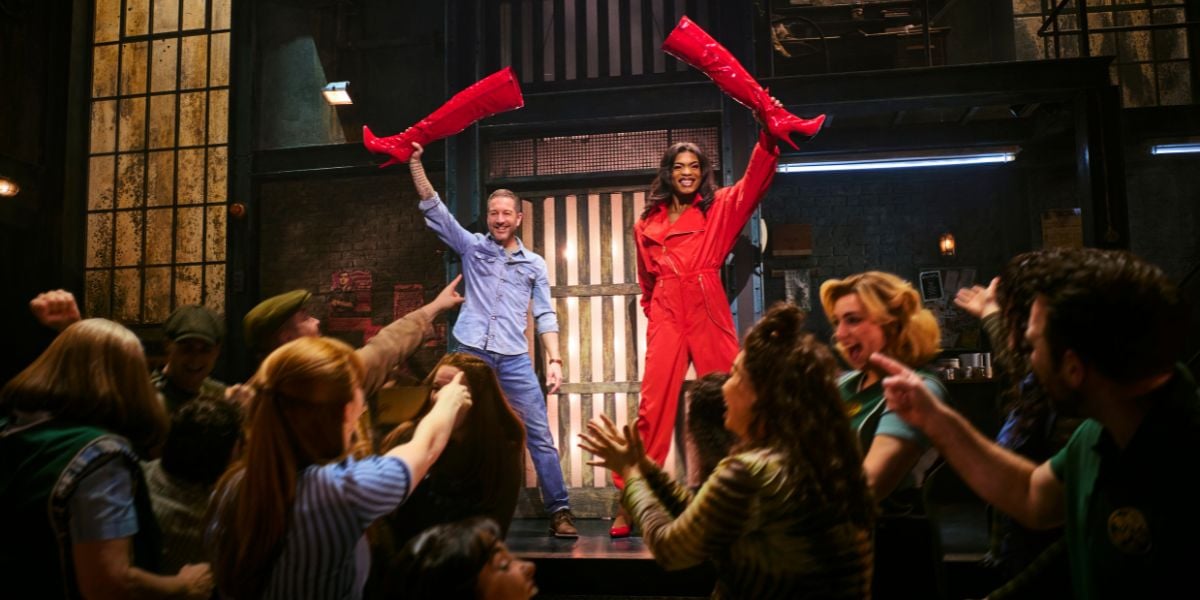 Johannes Radebe as Lola and Matt Cardle as Charlie Price, holding red heeled boots to the air.