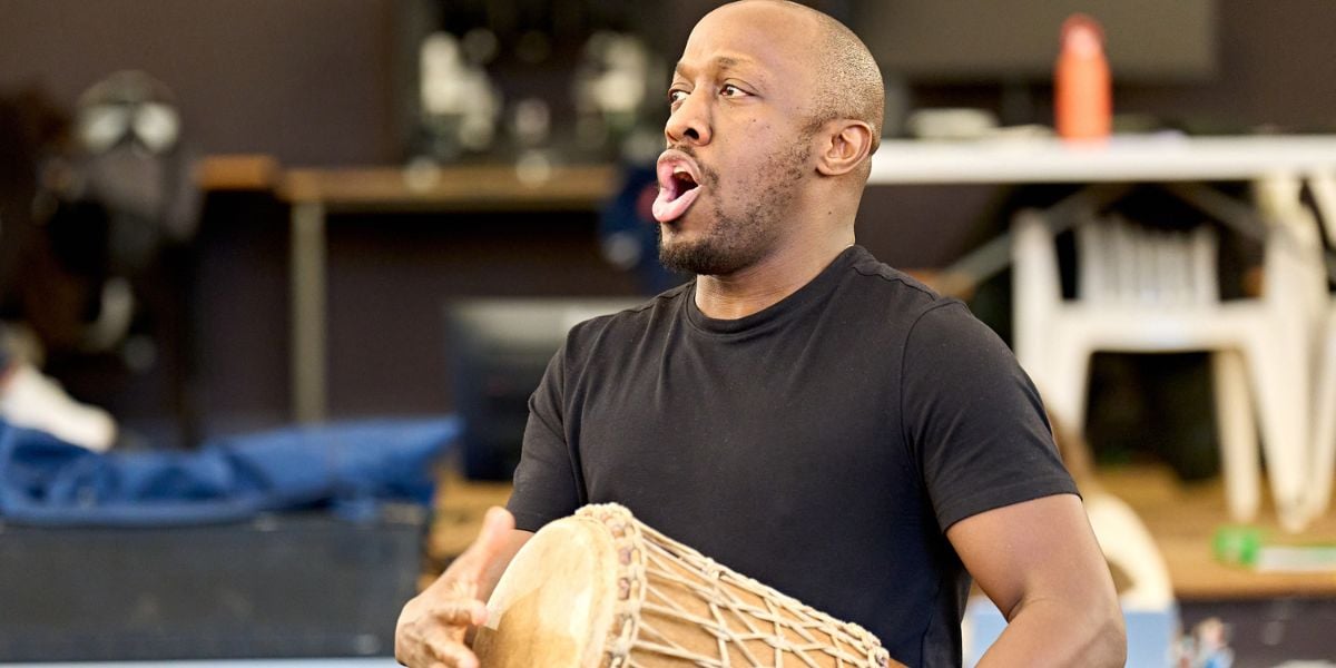 Giles Terera in rehearsals for One Flew Over the Cuckoo's Nest at the Old Vic. He is holding a drum and singing. 