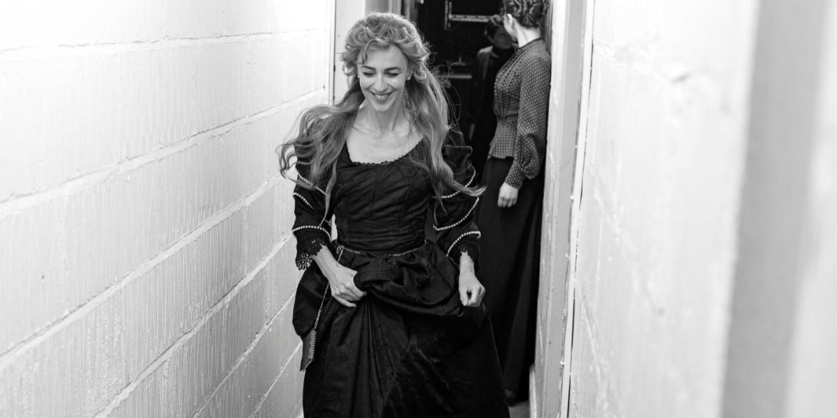 Grace Pervades behind the scenes photos, starring Ralph Fiennes and Miranda Raison. Raison in costumes runs backstage in a tight corridor.