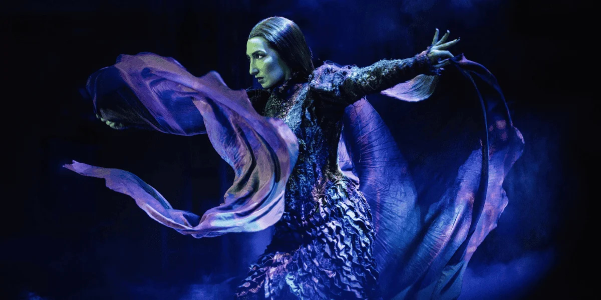 Emma Kingston dans le rôle d’Elphaba dans Wicked London. Elle porte une longue robe drapée